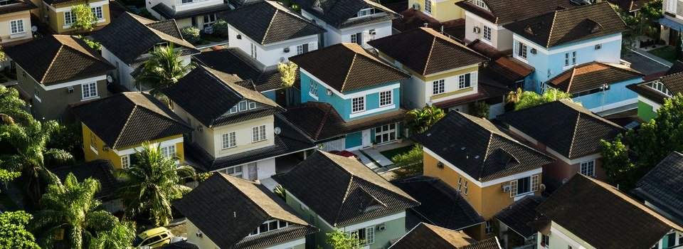 Bairro residencial visto de cima, ilustrando o acesso &agrave; casa pr&oacute;pria com rent-to-own e blockchain